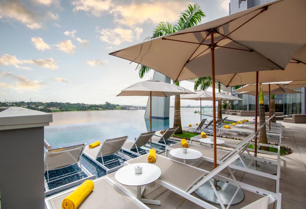 阿比让Noom Hotel Abidjan Plateau的一个带桌子和遮阳伞及水的庭院