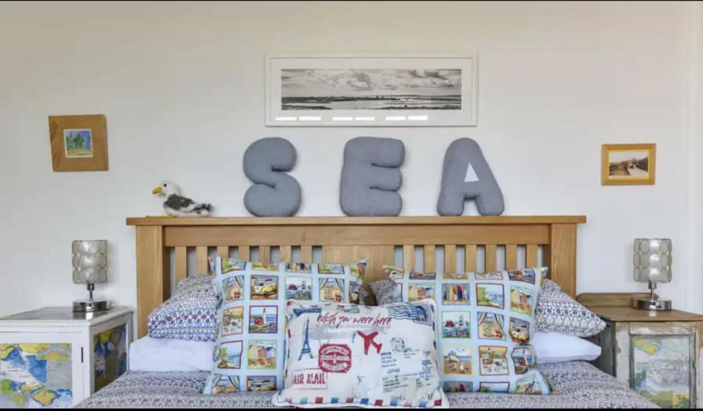 Hill HeadSolent Sea View beach Cottage的卧室配有一张床铺,墙上写着海字