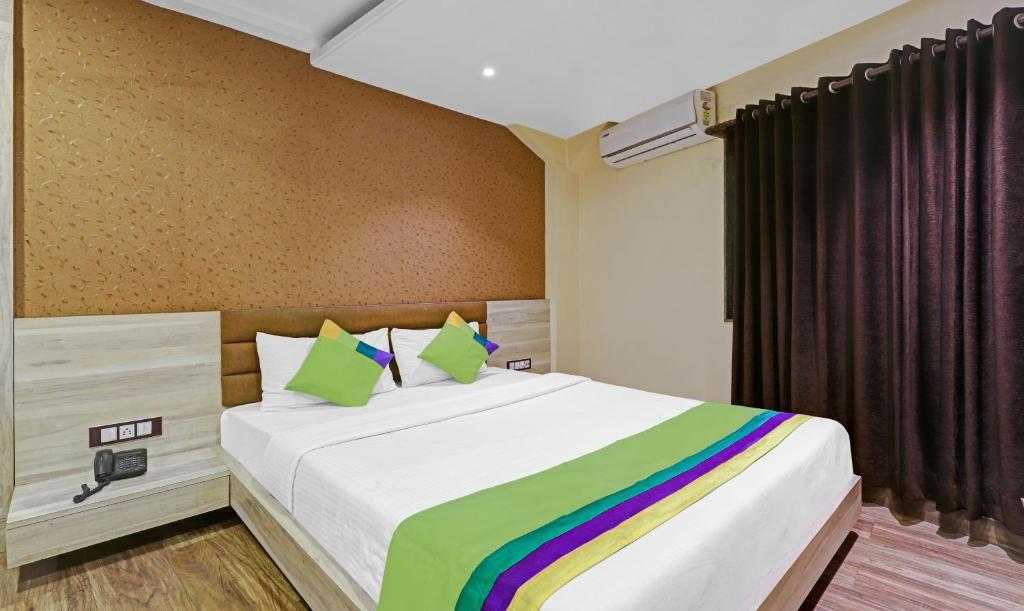 古瓦哈提Treebo Trend Apollo的一间卧室配有一张大床和彩虹毯子