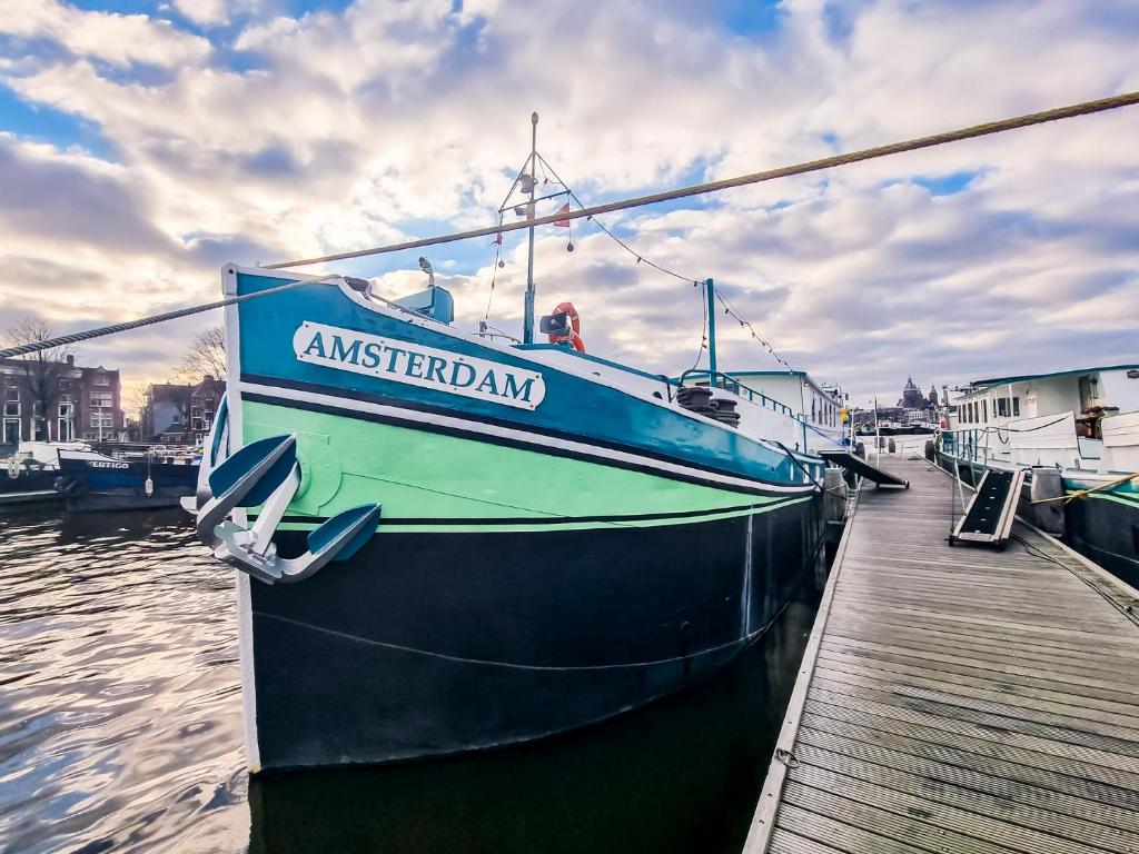 阿姆斯特丹Amsterdam Hotelboat的蓝色的船停靠在码头