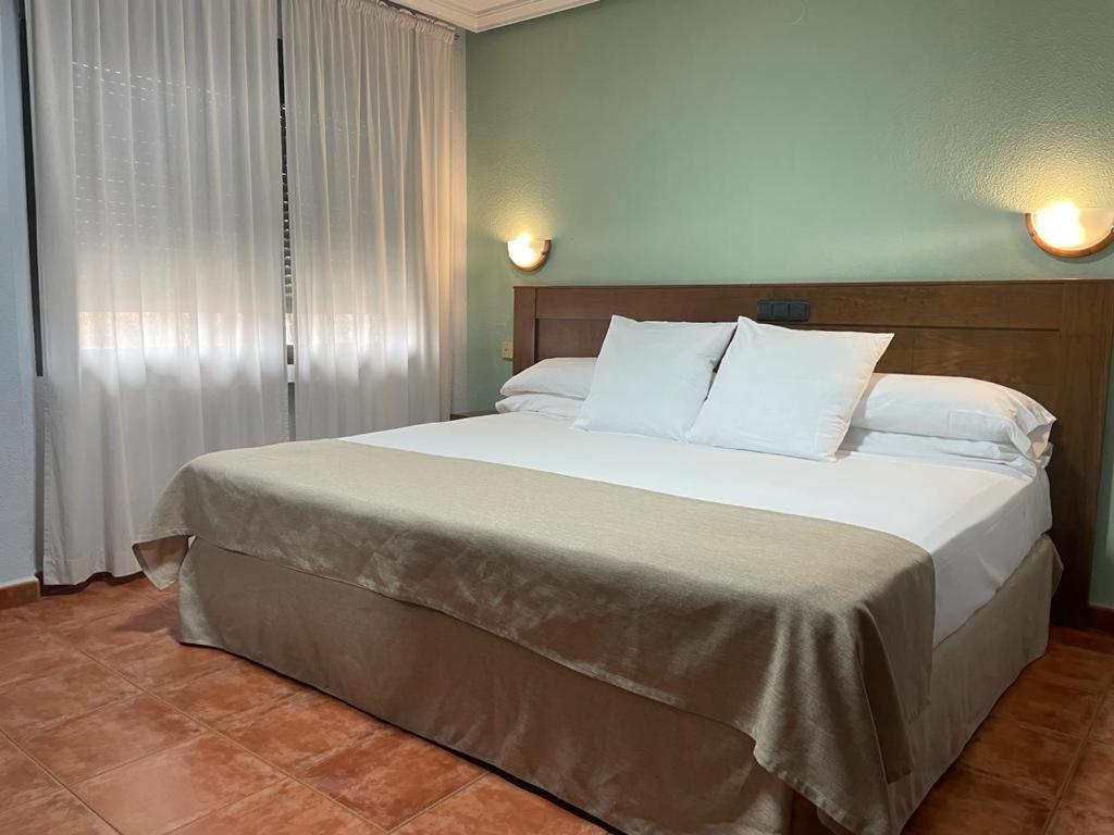 科里亚Hotel Los Kekes的卧室配有带白色枕头的大床
