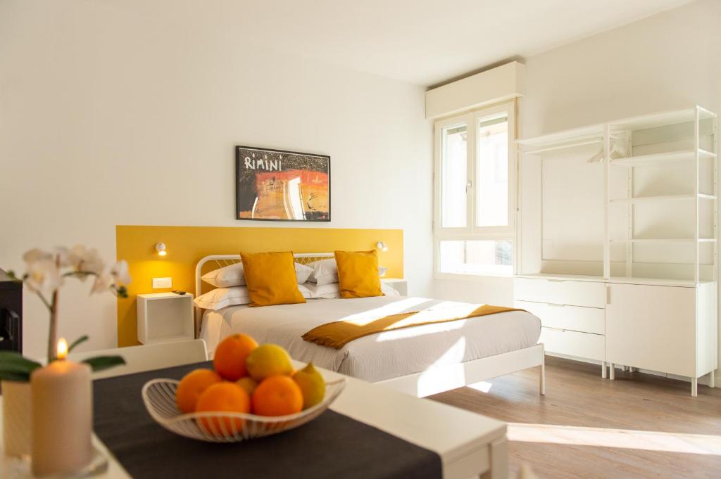 里米尼Corso51 Suite Apartments的一间卧室配有一张床,桌上放着一碗水果