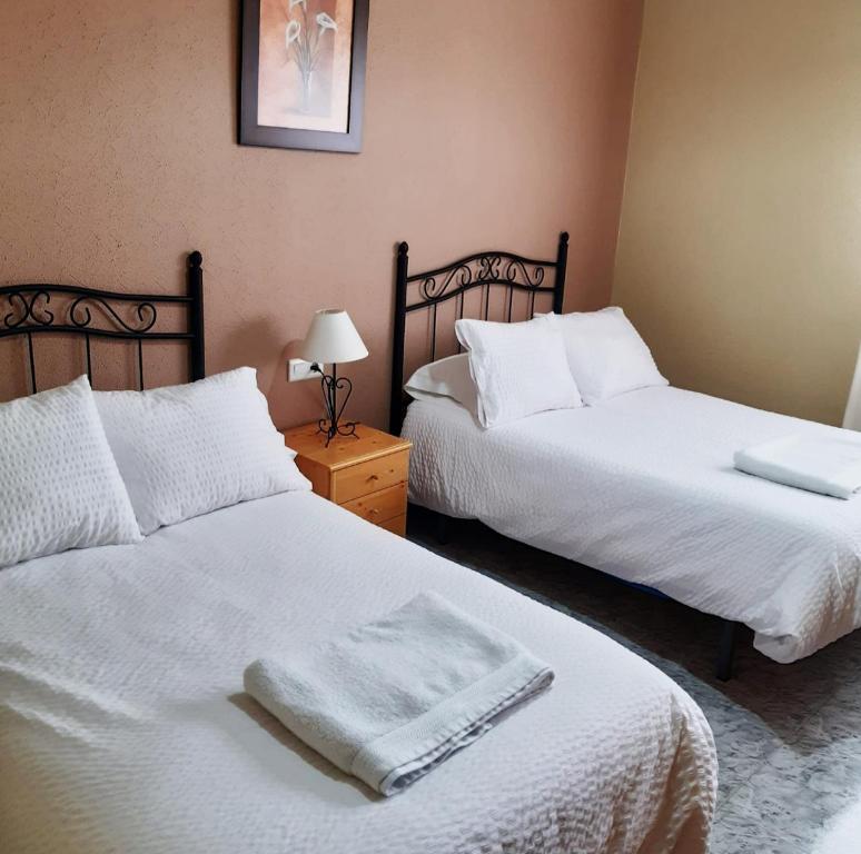 El Real de la JaraAlojamiento Mª Carmen的一间卧室配有两张带白色床单的床