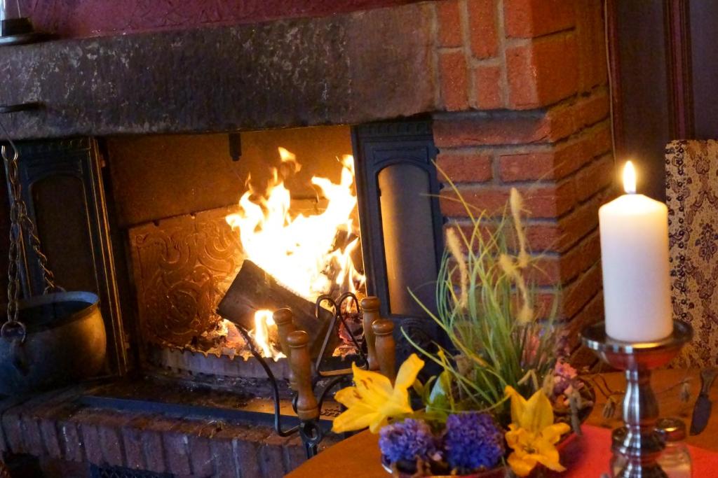 塞森Landhaus Zum alten Fritz的砖砌壁炉的火炉,壁炉上放着蜡烛和鲜花