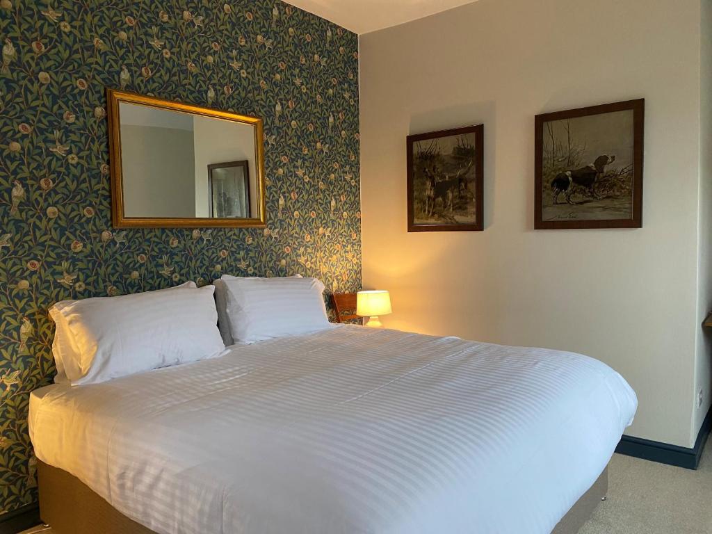 TimsburyThe Seven Stars的卧室配有一张带镜子和壁纸的白色床