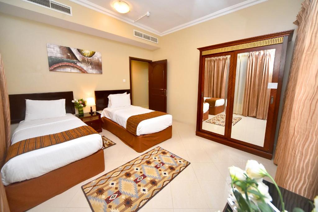 沙迦沙迦伊米瑞特明星沙迦公寓酒店的酒店客房,设有两张床和镜子