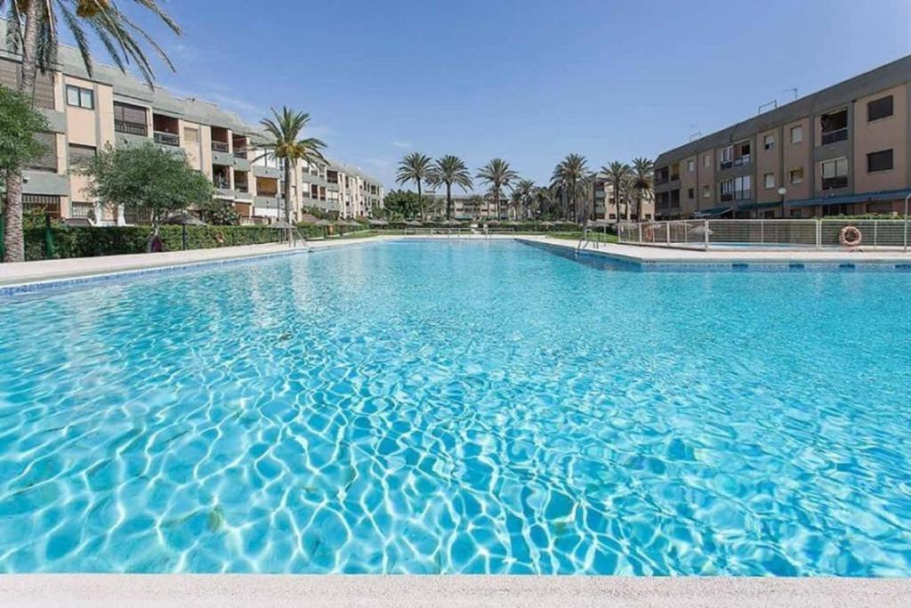 雷塔马尔LA PLAYA的一座种植了棕榈树和建筑的大型蓝色游泳池