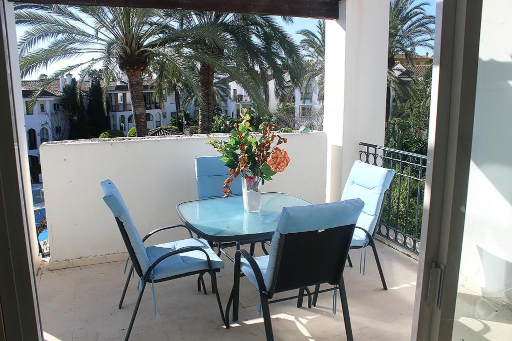 EsteponaHacienda Beach的棕榈树阳台的蓝色桌椅