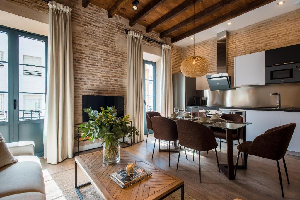 塞维利亚La Sillería de Triana by Magno Apartments的厨房以及带桌椅的起居室。
