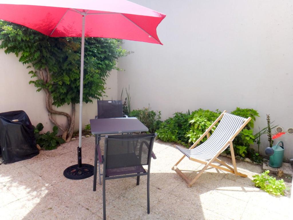 拉弗洛特Holiday Home La Touche - IDR120 by Interhome的一张桌子和椅子旁的红伞