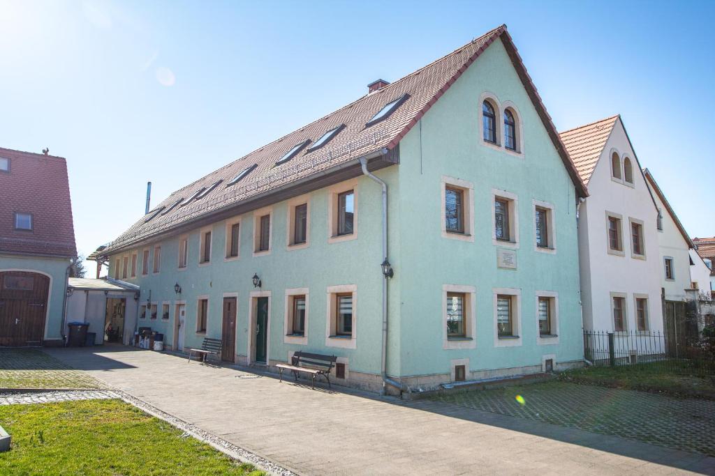 德累斯顿Ferienhaus -Am alten Dorfplatz-的一座蓝色和白色的大建筑,前面设有长凳