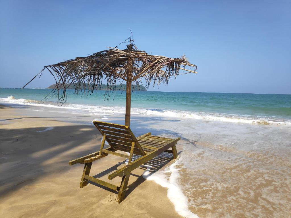 额布里Oliver`s Laguna ECO Lodge Hotel的一把椅子坐在海滩上,配有遮阳伞