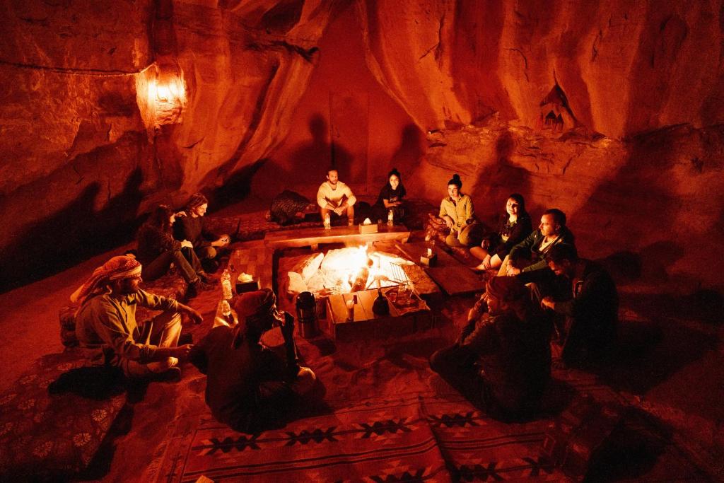 瓦迪拉姆Bedouin Nights Camp的一群人坐在洞穴里的火堆旁