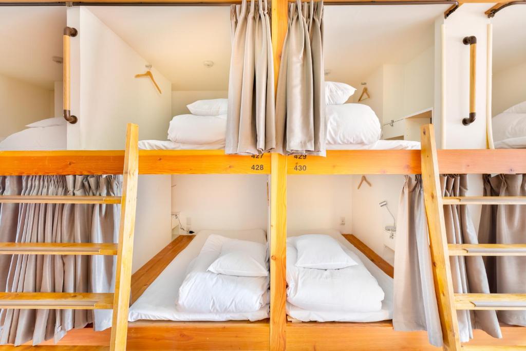 大阪Hostel OGK的宿舍间设有4张双层床和白色床。