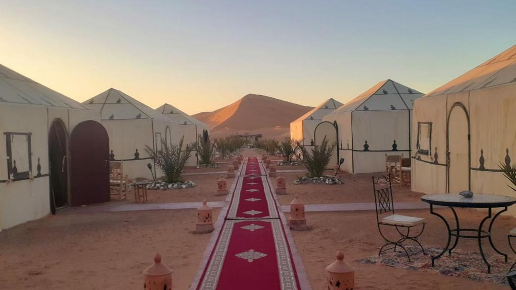 梅尔祖卡Sahara Tours luxury camp的沙漠中一排配有桌椅的建筑物