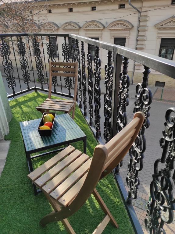 塞格德City Art Inn的阳台配有椅子和长凳,位于草地上