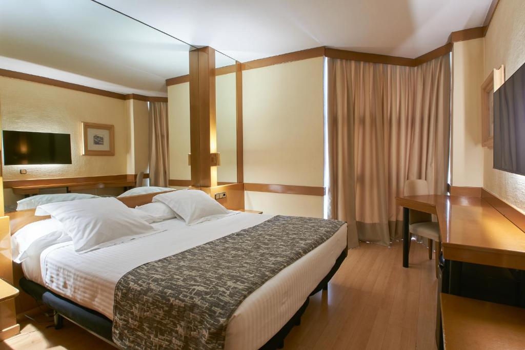 塞哥维亚洛斯阿科斯酒店的酒店客房设有一张大床和一张书桌。