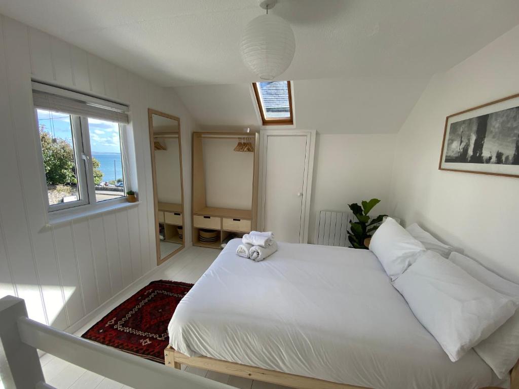 毛斯尔Cheerful one bedroom cottage in Mousehole.的卧室配有白色的床和窗户。