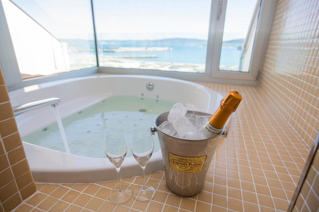 拉赫Hotel Boutique O Náutico Laxe的浴室配有带玻璃杯的浴缸和1瓶香槟