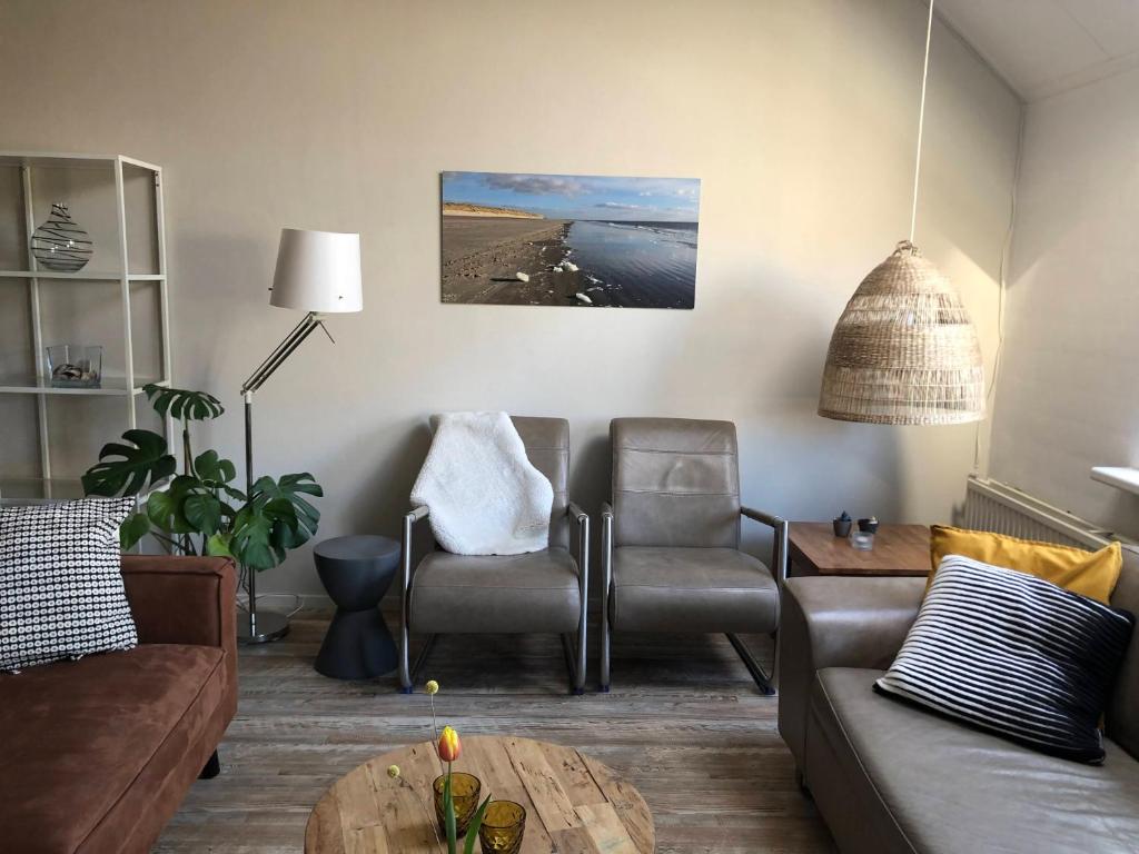 比伦Naar Zee op Ameland的客厅配有沙发、椅子和桌子