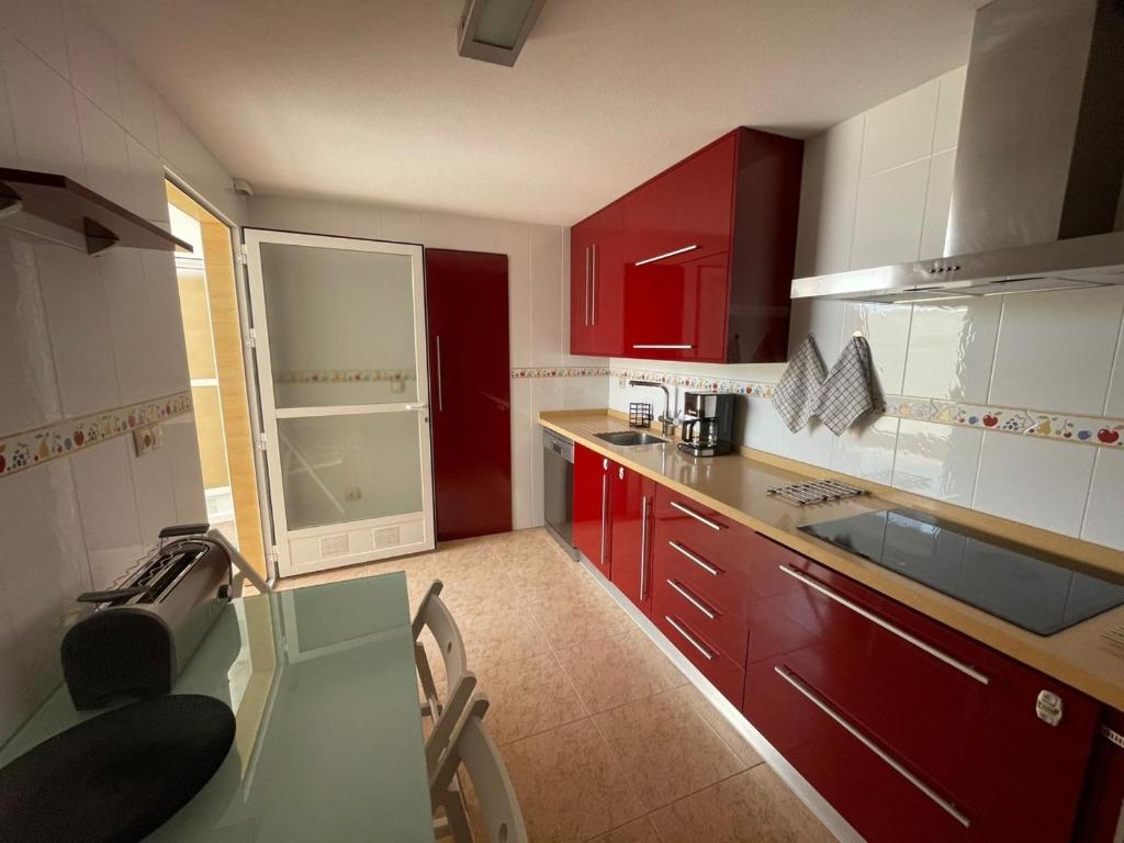 阿桂拉斯Casa Moraira的一间厨房,配有红色橱柜和玻璃桌