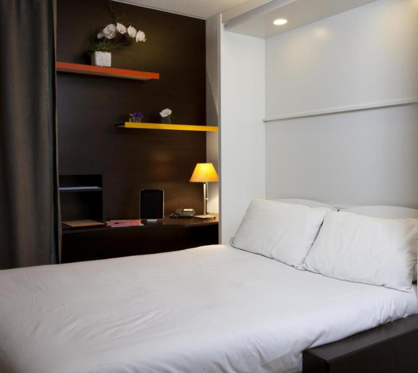 图卢兹At家庭公寓酒店的卧室配有白色的床和书桌
