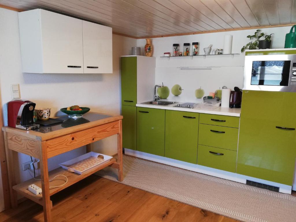 阿尔贝施文德Gemütliche Wohnung in Einfamilienhaus的厨房配有绿色橱柜和木桌