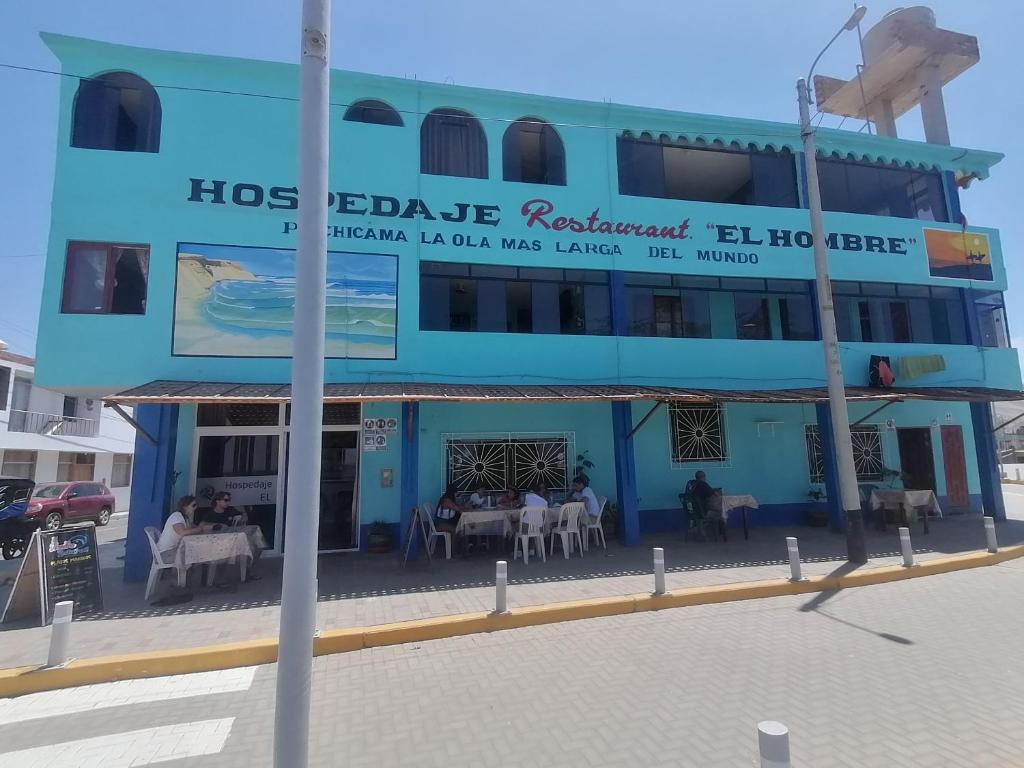 奇卡马港Hospedaje Restaurante El Hombre的一座蓝色的建筑,前面设有桌椅
