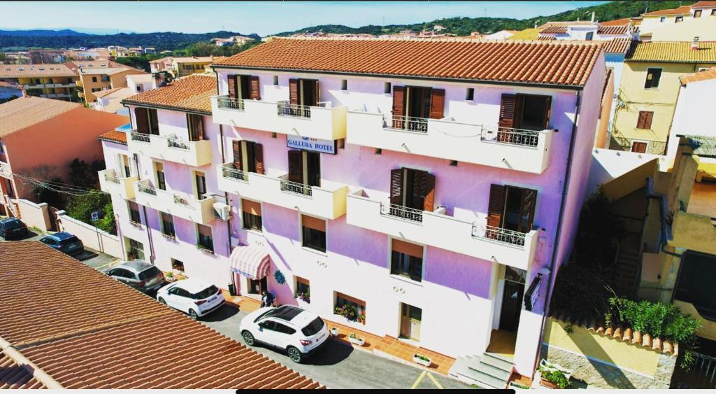 圣特雷莎加卢拉Gallura Hotel的一座大型建筑,前面有汽车停放