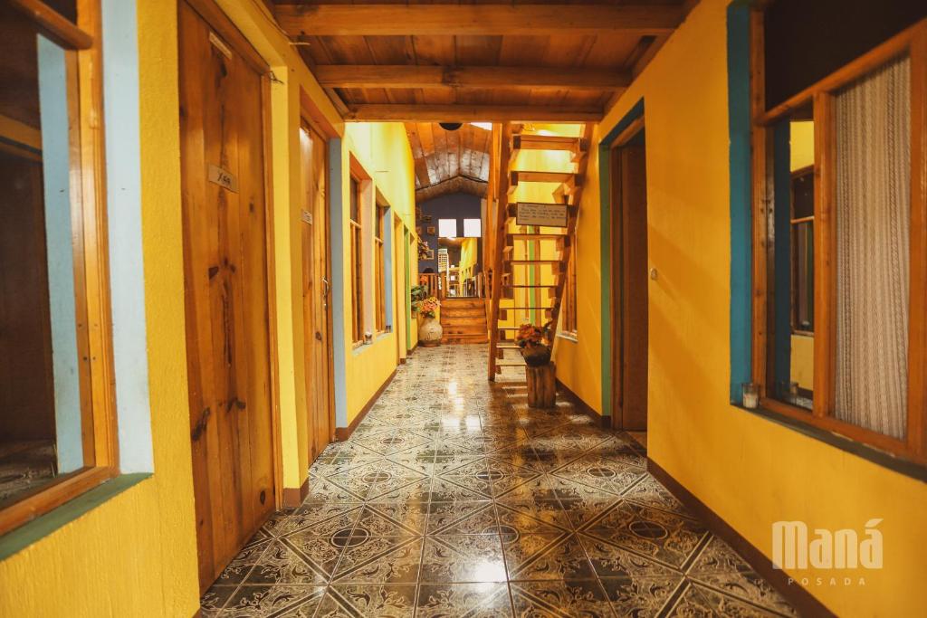 圣胡安拉拉古纳Posada Maná的一条空的走廊,有黄色的墙壁和瓷砖地板