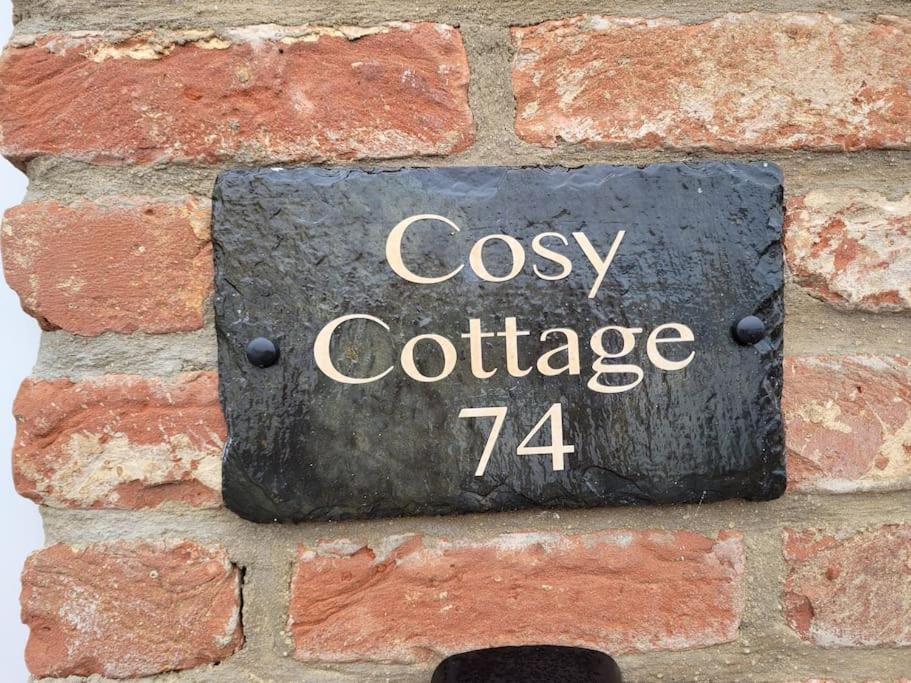 大德里菲尔德Cosy Cottage,The Paddock BARMSTON. NR BRIDLINGTON的一张在砖墙上的标志,上面是读到舒适的小屋的标志