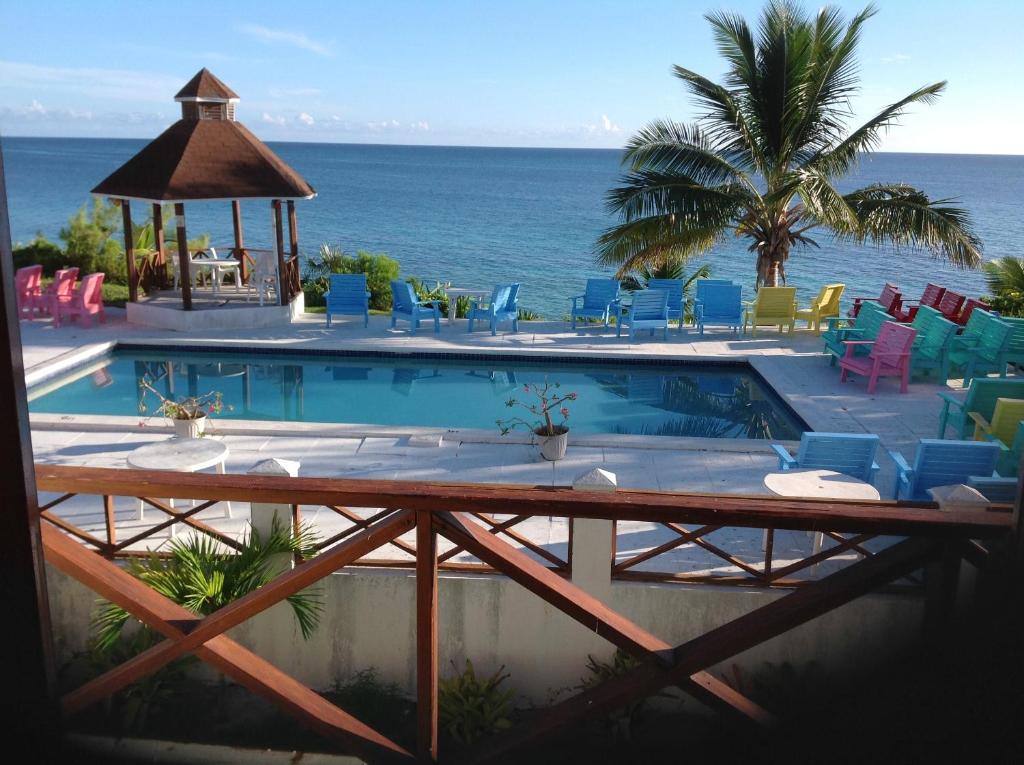 总督港尤妮克乡村酒店的一个带椅子的游泳池,背景是大海