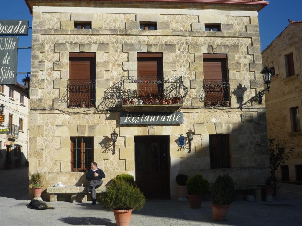 桑托多明戈德锡洛斯Hotel Rural Villa de Silos的坐在大楼前长凳上的男人