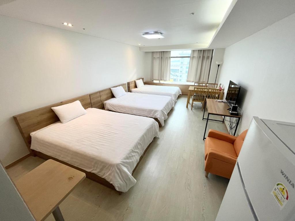 仁川市Incheon Airport Guesthouse的酒店客房设有两张床和一张桌子。
