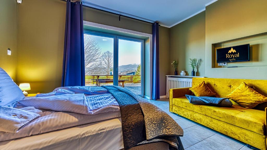 斯克拉斯卡波伦巴Apartamenty ROYAL APARTS Zielona Poręba - z panoramą gór的一间卧室配有一张大床和一张黄色的沙发