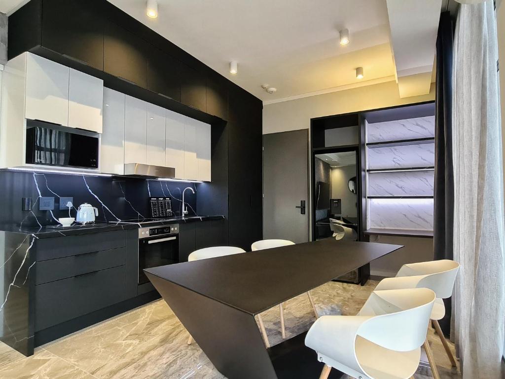 比勒陀利亚Luxurious Menlyn Maine 1 Bedroom on 12th Floor with Stunning Views & No Load Shedding的黑色的厨房配有白色的椅子和桌子