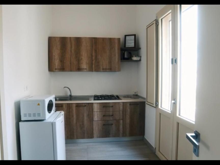 乌真托TORRE SUL MARE affittacamere Ugento的厨房配有木制橱柜和白色微波炉