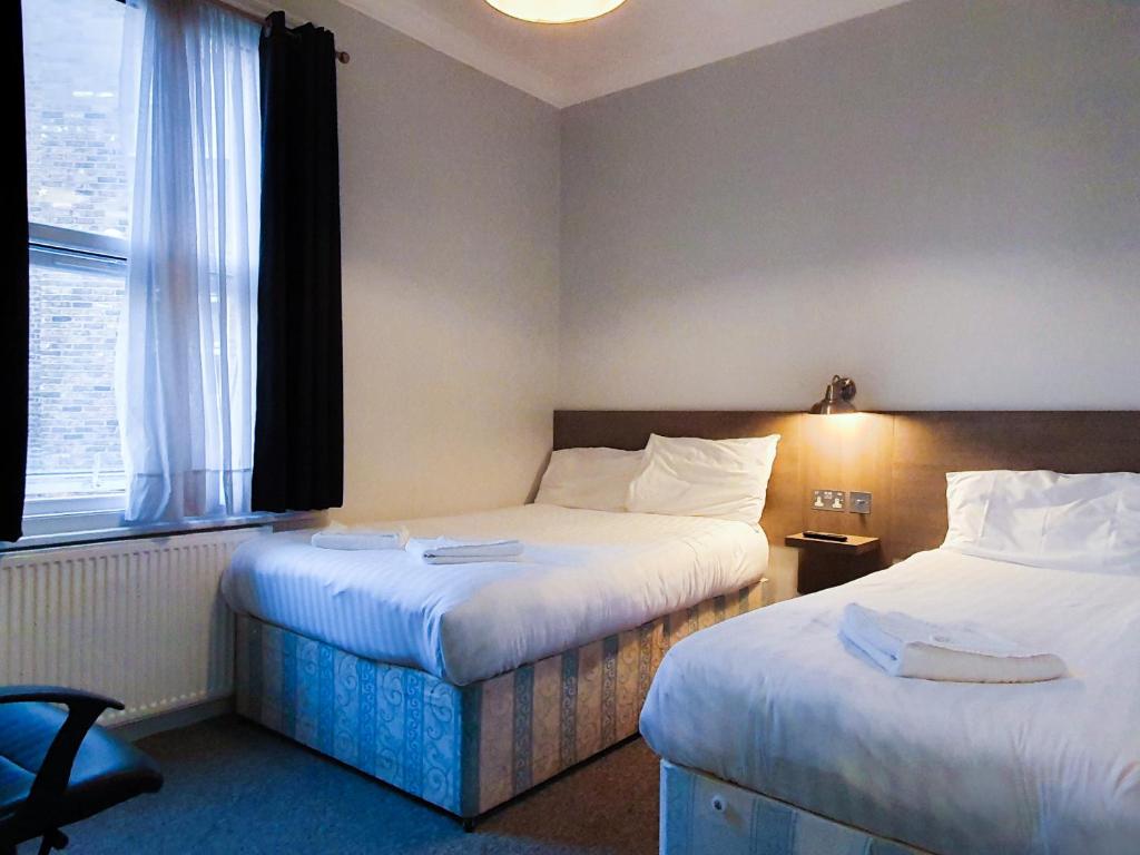 伦敦广场酒店的酒店客房设有两张床和窗户。