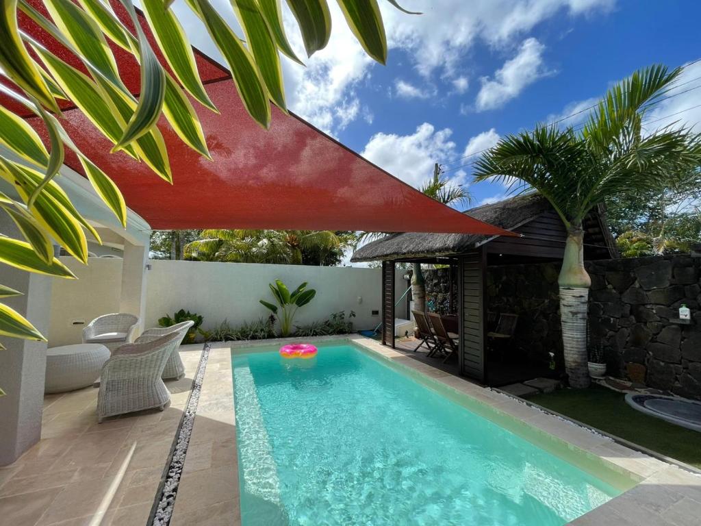 格兰贝伊HappInès Villa 3 bedroom Luxury Villa with private pool, near all amenities and beaches的一座房子上方的游泳池,上面有红伞