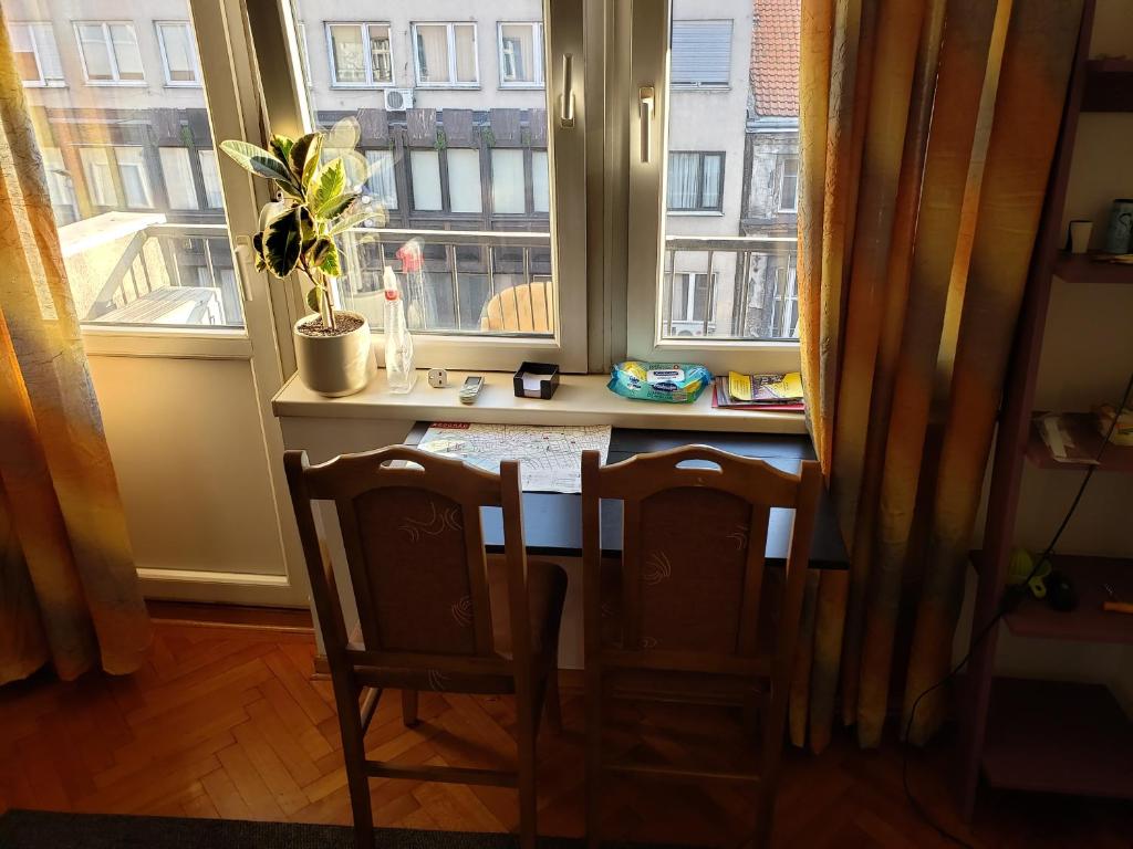 贝尔格莱德Cozy room in appartment, with shared bathroom,downtown Belgrade的窗前的一张桌子和两把椅子