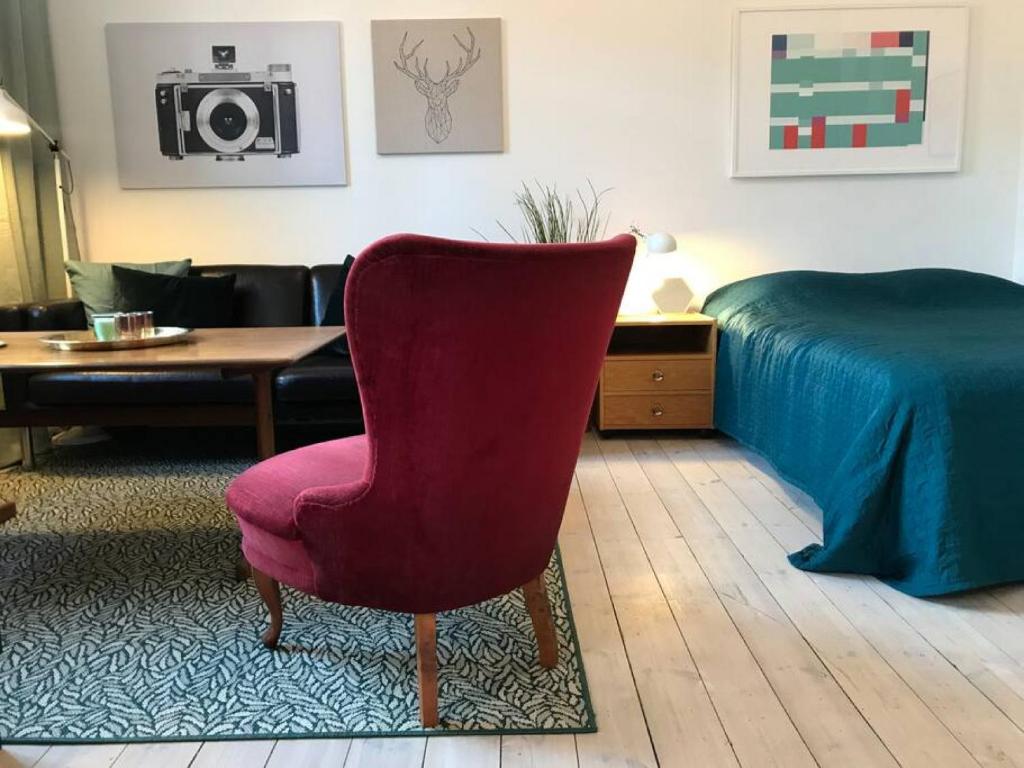 斯德哥尔摩Bohemian and light one room apartment in SoFo 31sqm的客厅配有红色椅子和一张床