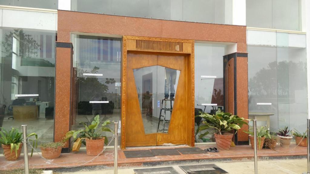 班加罗尔Airport Residency的一座种植了盆栽植物的建筑里的一个大型木门