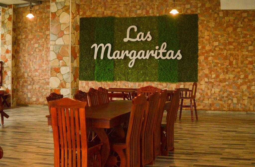 PerquínHotel y Restaurante Las Margaritas的一间设有桌椅的餐厅,还有标有玛格丽塔斯的标语
