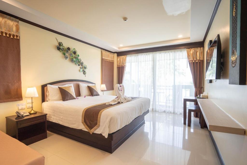 卡伦海滩Baan Sailom Hotel Phuket - Sha Extra Plus的一间卧室配有一张床、一张书桌和一个窗户。