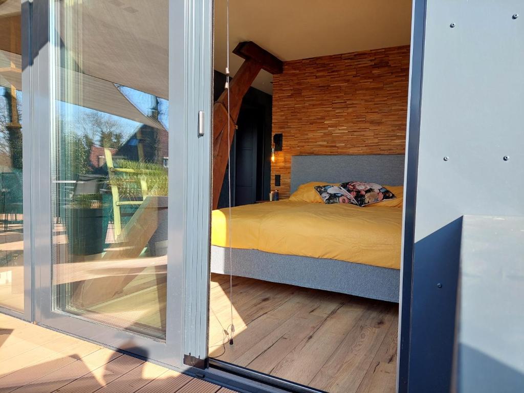 VierlingsbeekB&B Vierlingsbeek, Appartement Onder één dak en tuin-chalet的卧室设有一张通过滑动玻璃门的床铺。