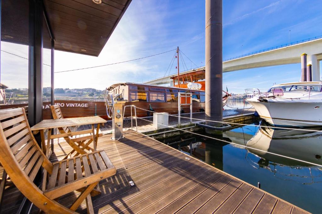 波尔图Oporto Douro Floating House的木甲板上设有长凳和水上船只
