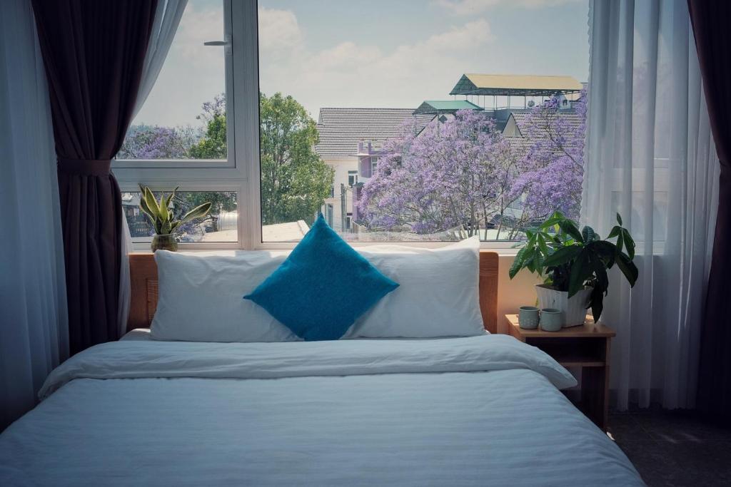 大叻RAON Villa - STAY 24H的窗前带蓝色枕头的床