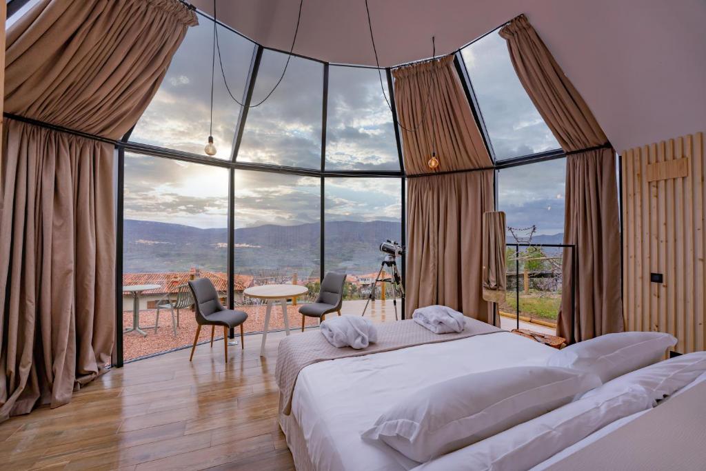 埃尔托尔诺Glamping El Regajo Valle del Jerte的一间卧室设有床铺和大型玻璃窗