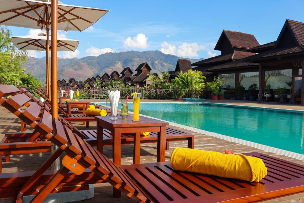 娘瑞KMA Inle Hotel的一个带游泳池和桌椅的度假村