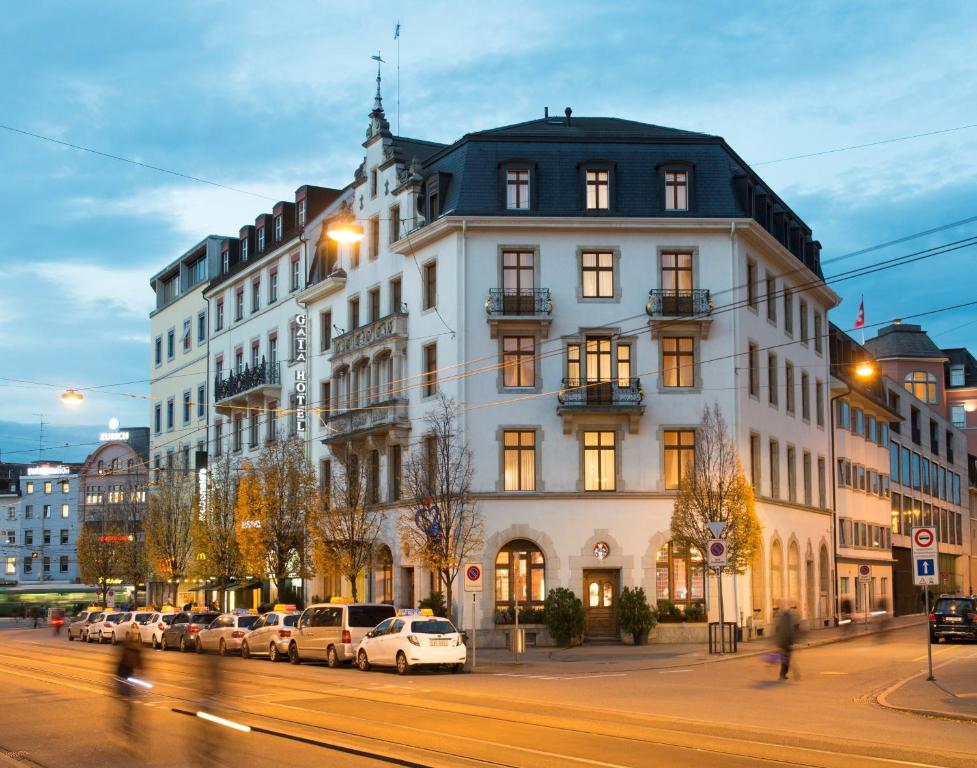 巴塞尔GAIA Hotel Basel - the sustainable 4 star hotel的一座白色的大建筑,前面有汽车停放